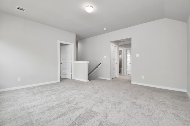 carpeted spare room featuring vaulted ceiling