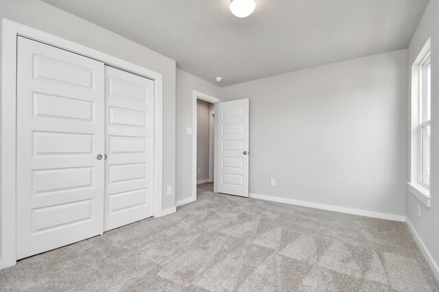 unfurnished bedroom featuring light carpet, a closet, and multiple windows