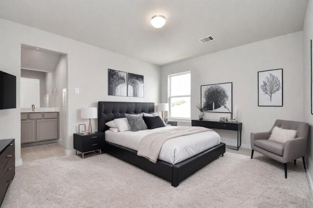 bedroom featuring ensuite bathroom and light hardwood / wood-style floors