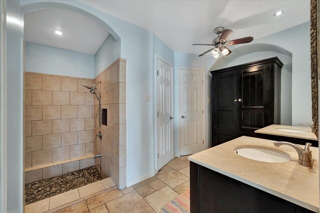 bathroom with a tile shower, vanity, and ceiling fan