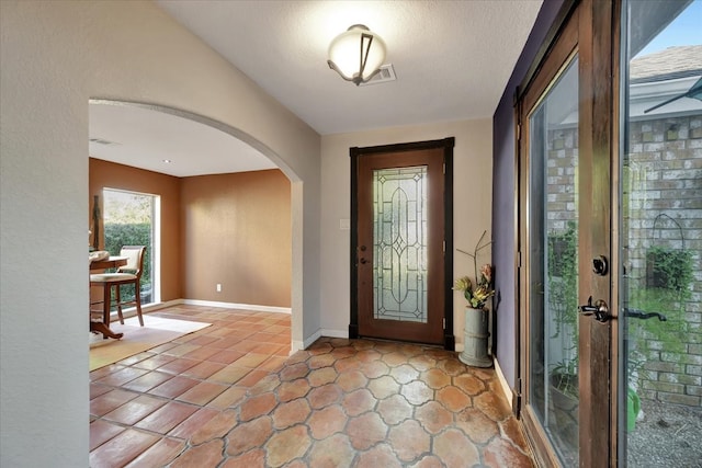 foyer with french doors, a textured ceiling, and light tile patterned floors