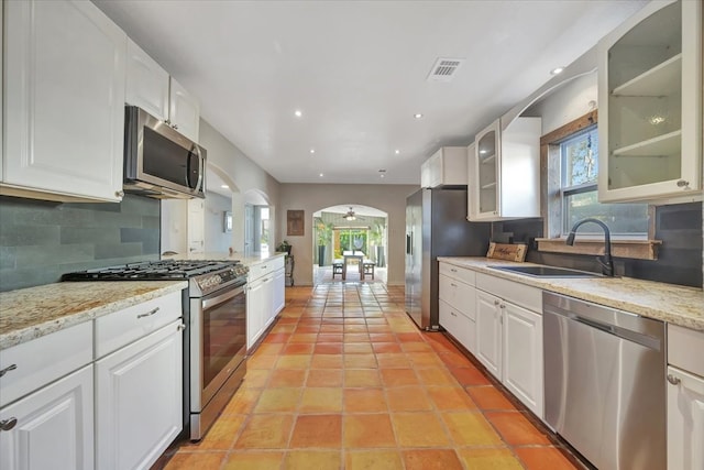 kitchen featuring white cabinets, sink, decorative backsplash, light stone countertops, and stainless steel appliances