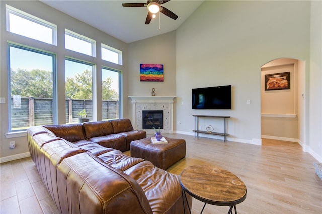 living room with a tile fireplace, light hardwood / wood-style flooring, high vaulted ceiling, and ceiling fan