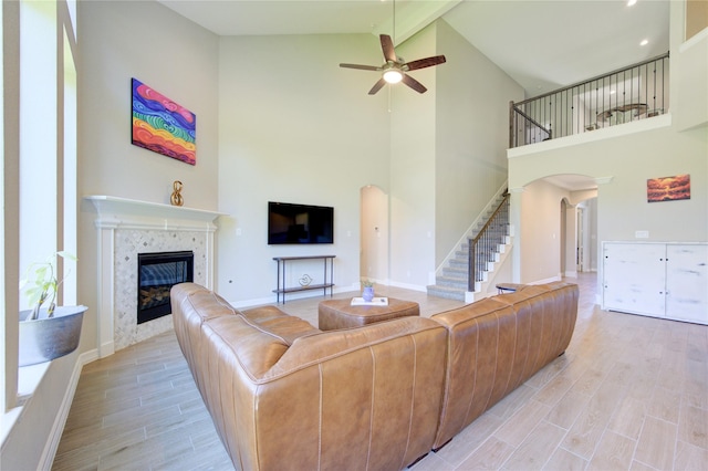 living room with high vaulted ceiling, ceiling fan, and a tiled fireplace