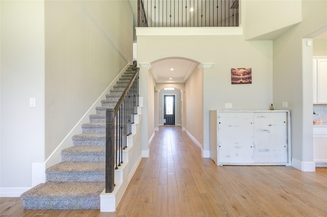 entrance foyer featuring light hardwood / wood-style flooring, a high ceiling, and ornamental molding