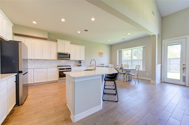 kitchen featuring a center island with sink, white cabinetry, sink, and appliances with stainless steel finishes