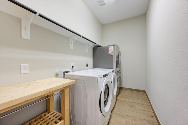 clothes washing area with washing machine and dryer and light hardwood / wood-style floors