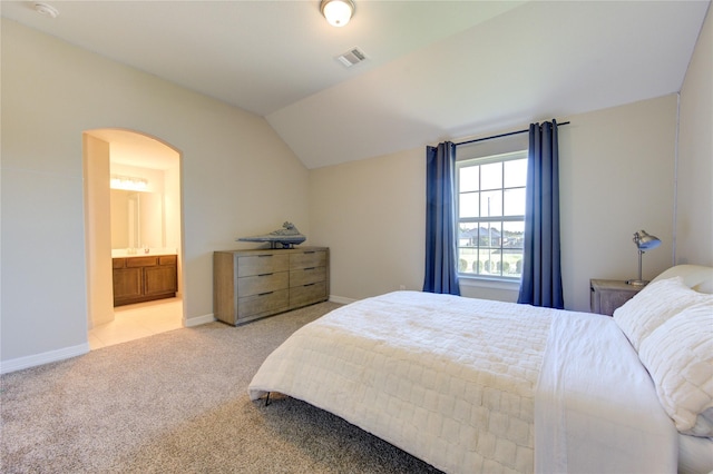 carpeted bedroom with ensuite bath and vaulted ceiling