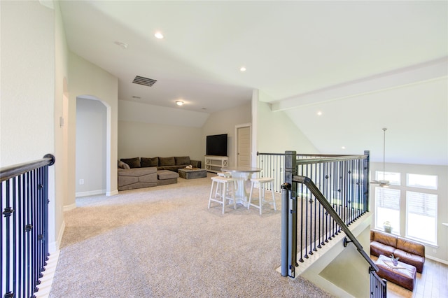 corridor with vaulted ceiling with beams and light colored carpet