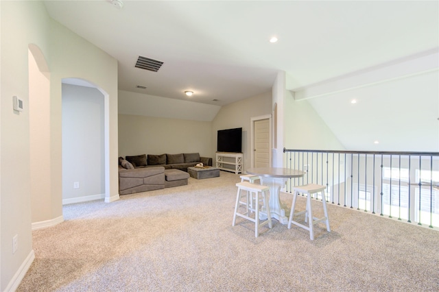 dining space featuring light carpet and lofted ceiling with beams