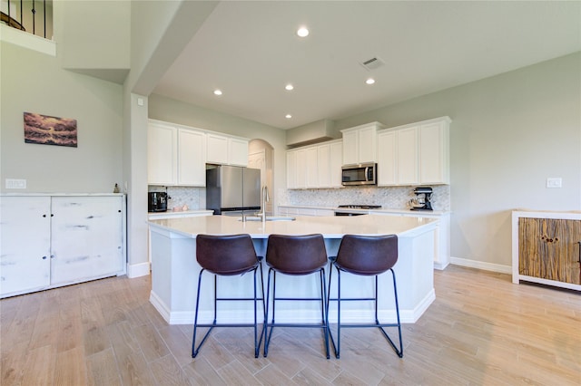 kitchen with white cabinets, a spacious island, appliances with stainless steel finishes, and a kitchen bar