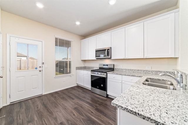 kitchen featuring light stone countertops, appliances with stainless steel finishes, sink, white cabinets, and dark hardwood / wood-style floors