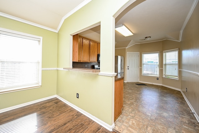 kitchen with hardwood / wood-style floors, vaulted ceiling, stainless steel refrigerator, and ornamental molding