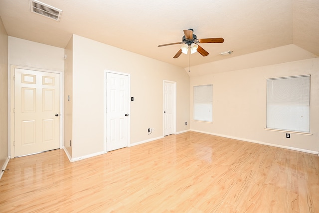 spare room with ceiling fan, vaulted ceiling, and light wood-type flooring