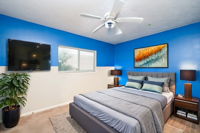 carpeted bedroom featuring ceiling fan and a textured ceiling