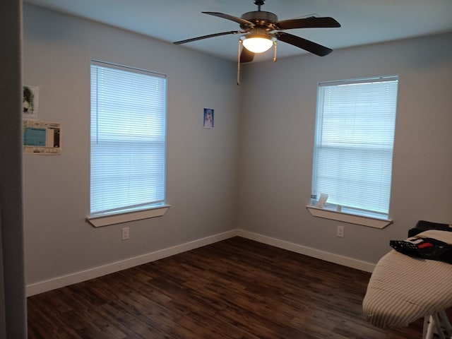 empty room featuring ceiling fan, a healthy amount of sunlight, and dark wood-type flooring