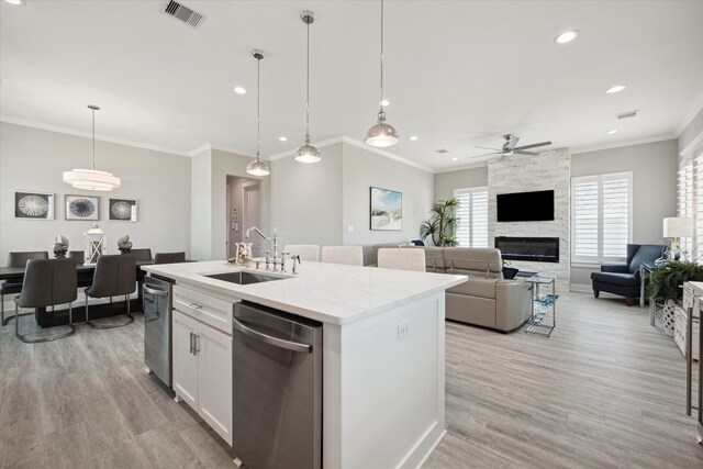 kitchen featuring pendant lighting, white cabinets, sink, ceiling fan, and an island with sink