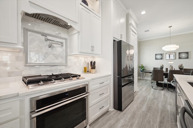 kitchen with white cabinets, crown molding, light wood-type flooring, light stone counters, and stainless steel appliances