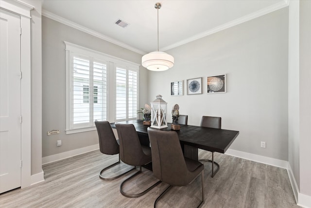 dining room with crown molding and light hardwood / wood-style flooring