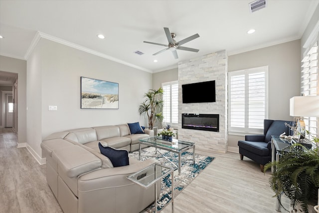 living room featuring ceiling fan, light hardwood / wood-style floors, ornamental molding, and a fireplace