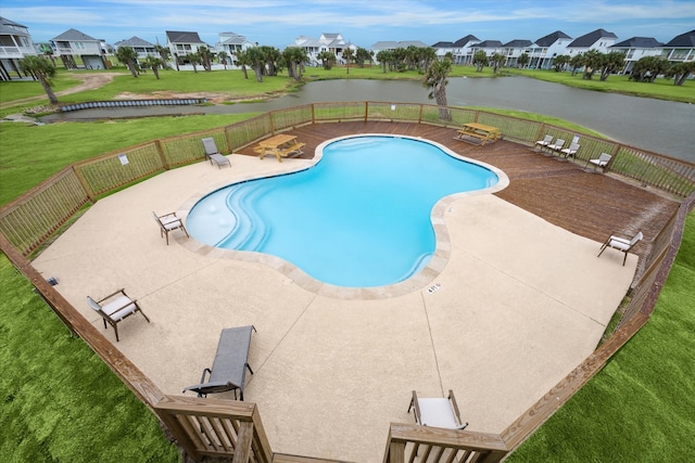 view of pool with a lawn, a water view, and a patio