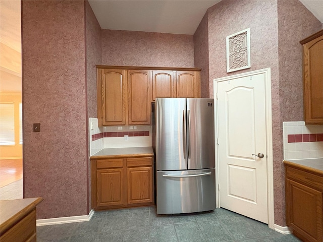 kitchen with decorative backsplash and stainless steel fridge