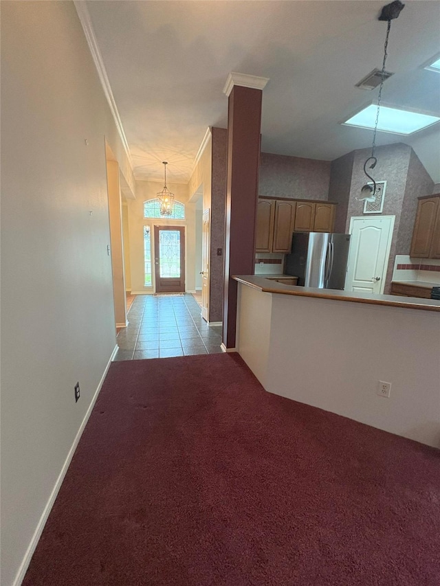 interior space with crown molding, vaulted ceiling, stainless steel fridge, light colored carpet, and a chandelier