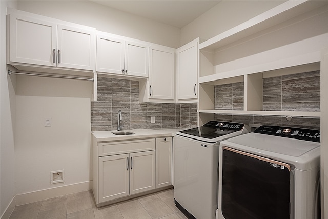 clothes washing area with cabinets, light tile patterned floors, washer and clothes dryer, and sink