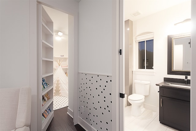 bathroom with built in features, hardwood / wood-style floors, vanity, and toilet