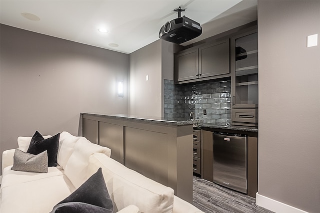 interior space with decorative backsplash, dark wood-type flooring, and stainless steel dishwasher