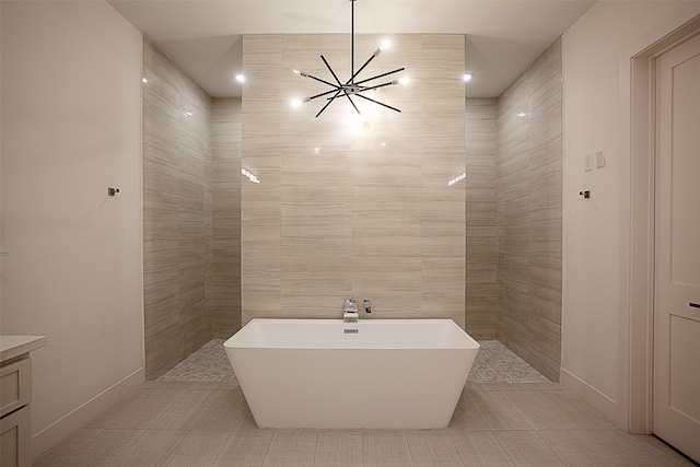 bathroom with tile patterned flooring, a bath, tile walls, and a chandelier