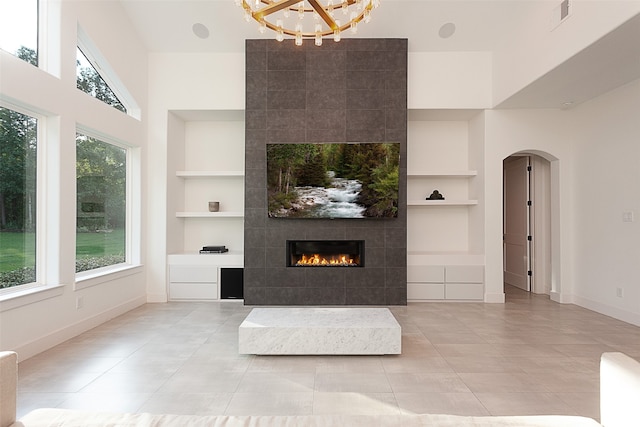 unfurnished living room with built in shelves, light tile patterned floors, and a tiled fireplace