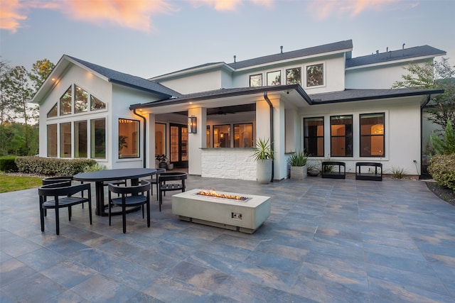 back house at dusk with an outdoor fire pit and a patio