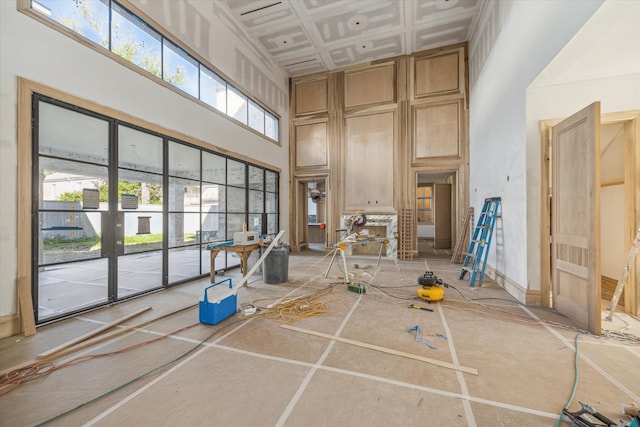 interior space featuring tile patterned floors, a towering ceiling, a healthy amount of sunlight, and coffered ceiling