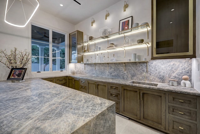 kitchen featuring light tile patterned floors, backsplash, stone countertops, and sink