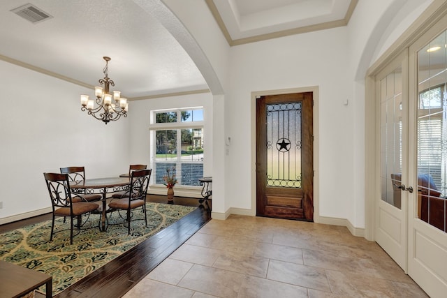 foyer entrance featuring an inviting chandelier, a textured ceiling, a wealth of natural light, and french doors