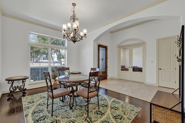 dining space with a notable chandelier, light hardwood / wood-style floors, ornamental molding, and french doors