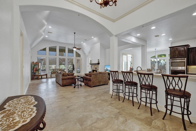 interior space featuring lofted ceiling, ceiling fan with notable chandelier, and ornamental molding