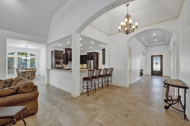 kitchen featuring dark brown cabinetry, stainless steel appliances, an inviting chandelier, kitchen peninsula, and decorative light fixtures