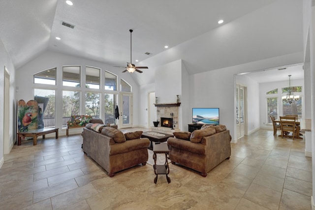 living room with ceiling fan with notable chandelier and high vaulted ceiling