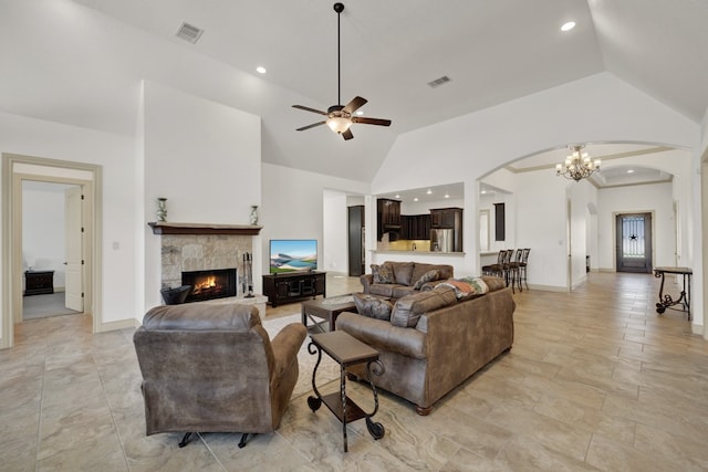 living room featuring ceiling fan with notable chandelier, a fireplace, and high vaulted ceiling