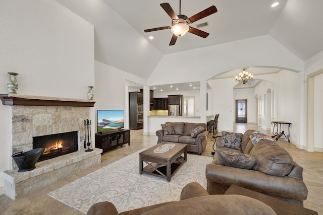 living room with ceiling fan with notable chandelier, a fireplace, and high vaulted ceiling