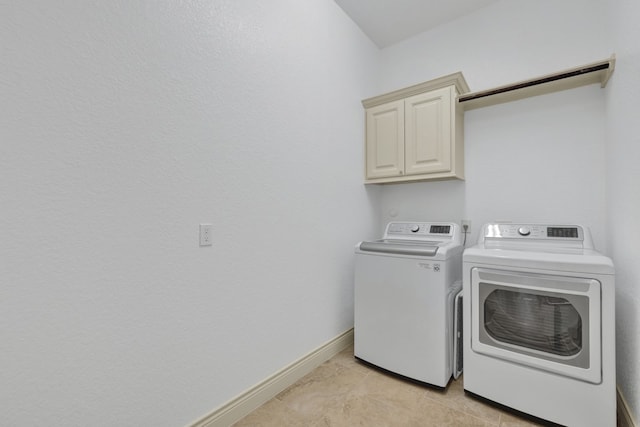 laundry area with washing machine and dryer, light tile patterned flooring, and cabinets