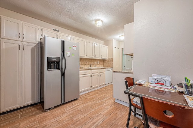 kitchen featuring dishwasher, stainless steel fridge, white cabinetry, and sink