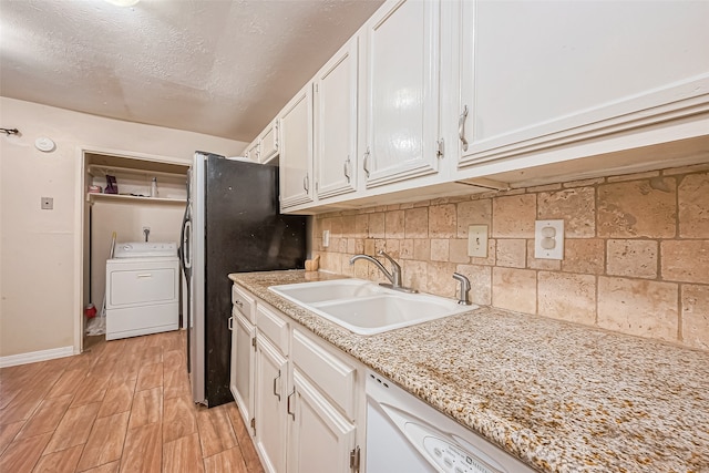 kitchen featuring stainless steel fridge, sink, light hardwood / wood-style flooring, white cabinets, and washer / clothes dryer