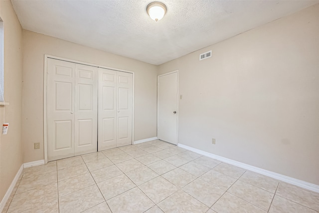 unfurnished bedroom with a closet, light tile patterned floors, and a textured ceiling