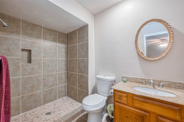 bathroom with a tile shower, vanity, and toilet