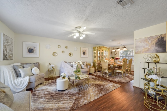 living room with a textured ceiling, ceiling fan, and dark hardwood / wood-style floors