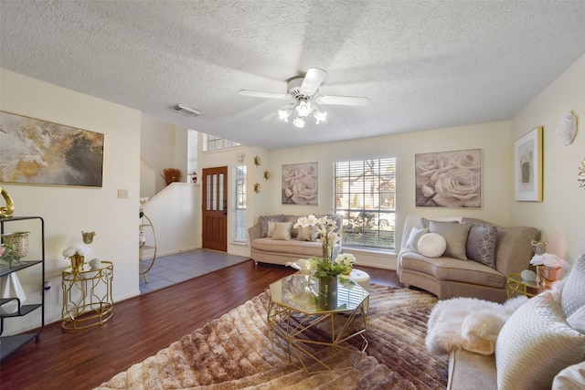 living room featuring ceiling fan, dark wood-type flooring, and a textured ceiling