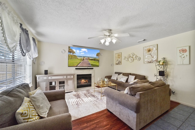 living room with a textured ceiling, ceiling fan, and dark hardwood / wood-style floors